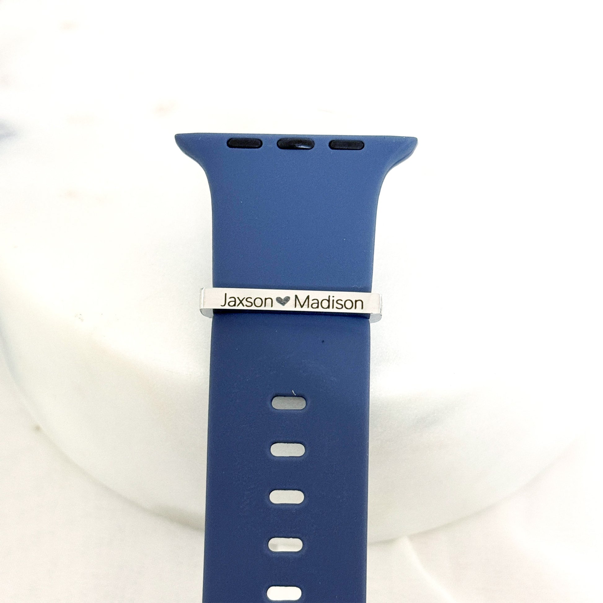 Personalized stainless steel watch band charm with custom engraving options, shown on a silicone watch band.