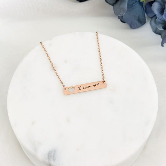 Personalized horizontal bar necklace with heart cut-out on the left side, custom engraved with unique handwriting.
