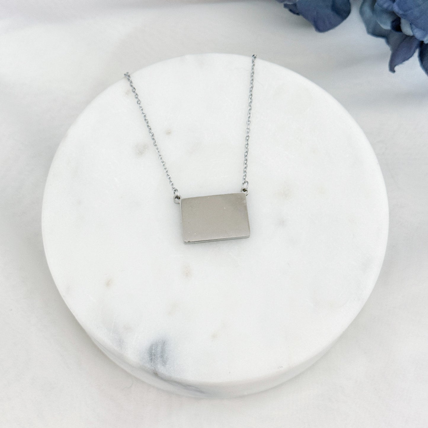 Veiled postcard necklace with hidden postcard, able to showcase customizable engravings and inclusions.